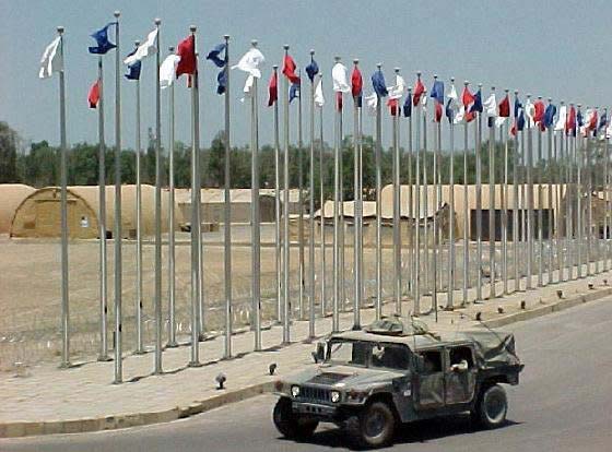 Military vehicle driving on the road with CAMSS30 shelter's in the background